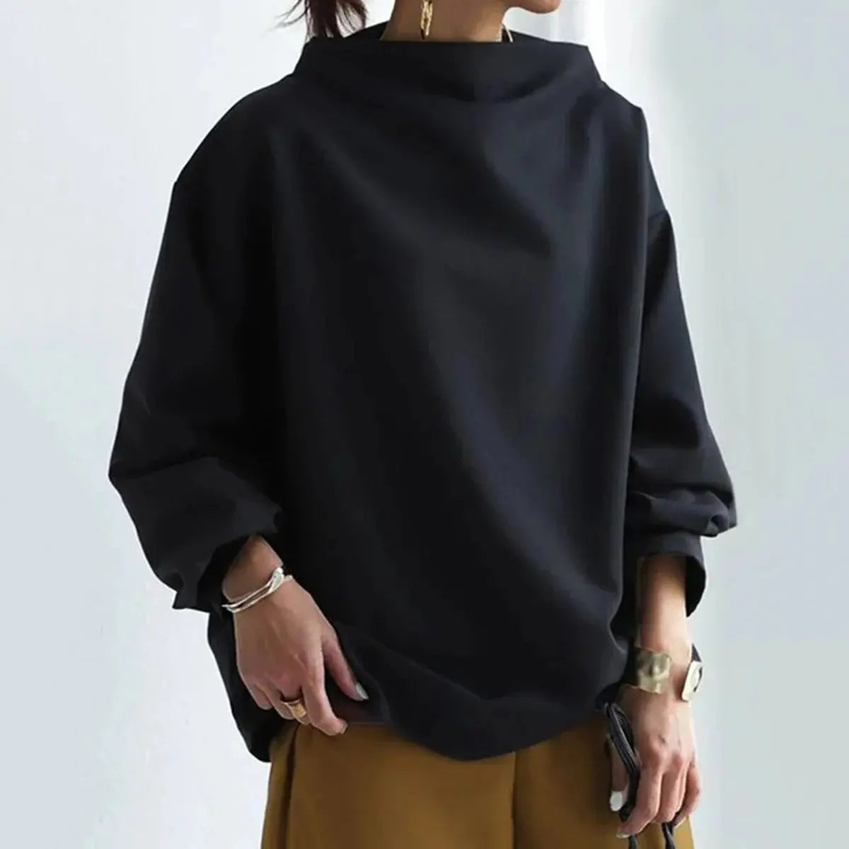Maglione nero oversize da donna, collo alto, maniche lunghe, stile casual, abbinato a pantaloni marroni. Moda autunnale elegante e confortevole.