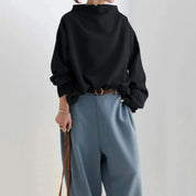 Donna con camicia nera oversize e pantaloni blu, cintura marrone, accessori minimal. Moda casual elegante, abbigliamento donna autunno.
