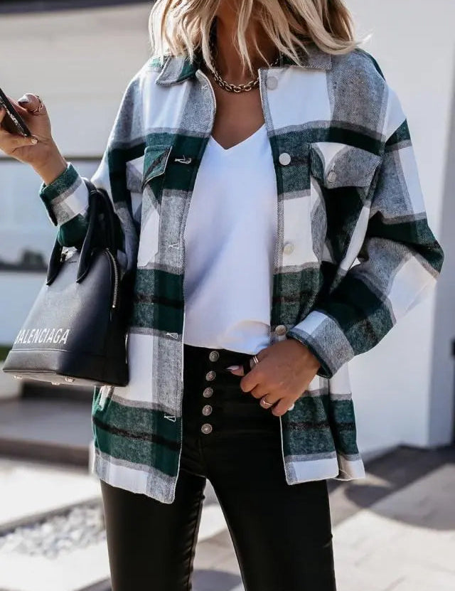 Donna con camicia a quadri verde e bianca, borsa nera Balenciaga, pantaloni neri, smartphone in mano. Moda casual autunnale.