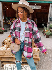 Donna con cappotto a quadri rosa e bianco, jeans strappati, borsa a tracolla beige, cappello beige, davanti a un mercato agricolo con zucche.