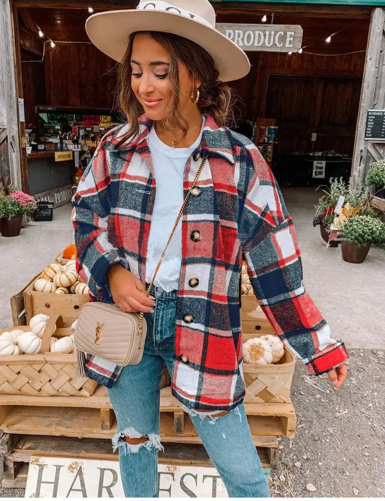 Giacca a quadri rossa e blu su donna con cappello beige, jeans strappati e borsa a tracolla, davanti a negozio di prodotti agricoli. Moda autunnale casual.