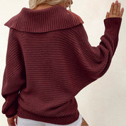 Maglione donna oversize marrone, lavorato a maglia, con collo ampio e maniche lunghe, indossato con pantaloncini bianchi. Moda autunnale casual.