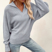 Maglione grigio donna in maglia a coste, maniche lunghe, scollo a V, abbinato a jeans chiari. Look casual e moderno per l'autunno.