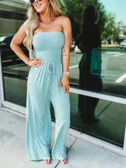 Donna con tuta intera azzurra, senza spalline, in posa all'aperto. Moda estiva, abbigliamento casual elegante, tuta donna trendy.