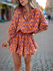 Abito corto donna arancione e blu con motivo ikat, maniche lunghe, scollo a V, indossato in strada. Moda femminile, abbigliamento estivo elegante.