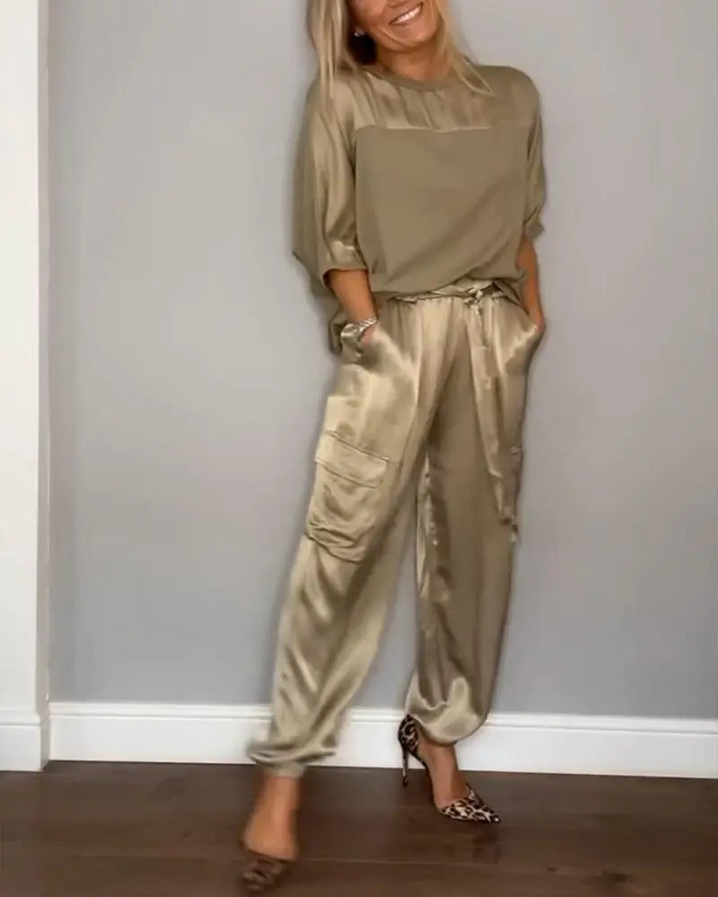 Donna in completo satinato beige, con pantaloni cargo e tacchi leopardati. Moda elegante, abbigliamento femminile, stile casual-chic.