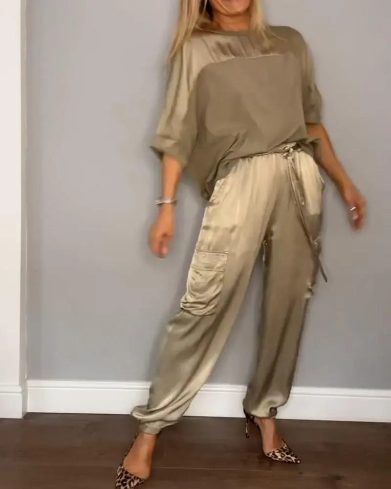 Donna in tuta elegante color oro, con pantaloni cargo e top coordinato, indossa tacchi leopardati. Moda femminile, abbigliamento casual chic.