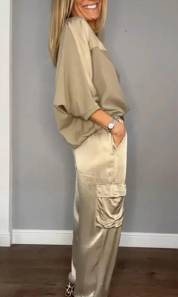 Donna in abbigliamento casual beige, camicia oversize e pantaloni cargo satinati, posa sorridente. Moda femminile elegante e confortevole.
