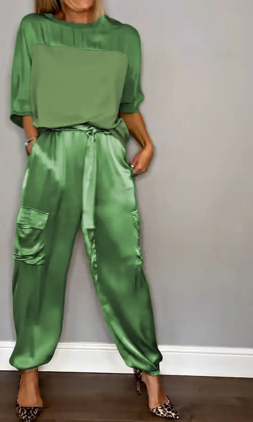 Donna con tuta verde satinata, tasche cargo, maniche corte, abbinata a tacchi leopardati. Moda elegante, abbigliamento femminile trendy.