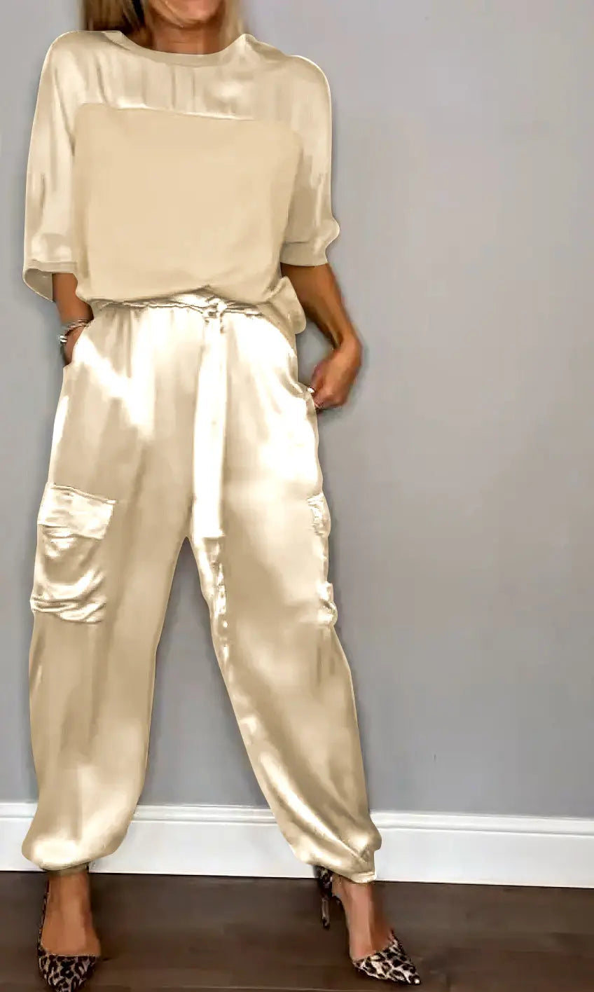 Donna in tuta elegante color crema, tessuto satinato, con tasche laterali, abbinata a scarpe leopardate. Moda femminile, abbigliamento chic.