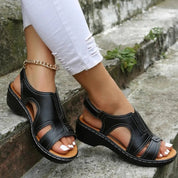 Sandali neri da donna con zeppa, cinturino alla caviglia dorato, suola antiscivolo, indossati con jeans bianchi strappati. Scarpe estive eleganti.