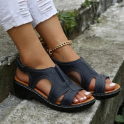 Sandali donna neri con tacco basso, design aperto, cinturino alla caviglia, indossati con jeans bianchi strappati. Scarpe estive eleganti e comode.