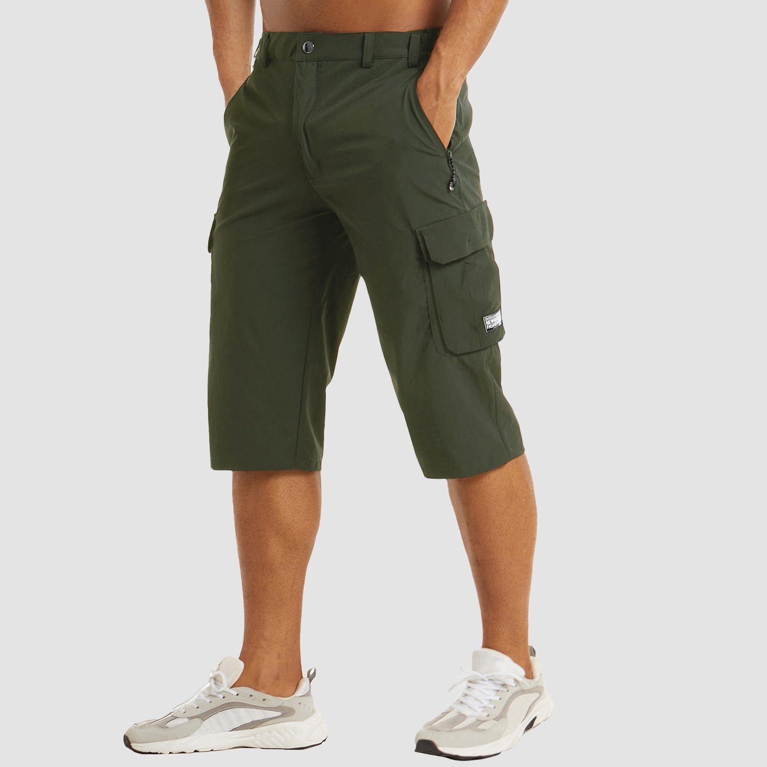 Pantaloncini cargo verdi da uomo, tasche laterali, lunghezza al ginocchio, stile casual, abbinati a scarpe sportive bianche.