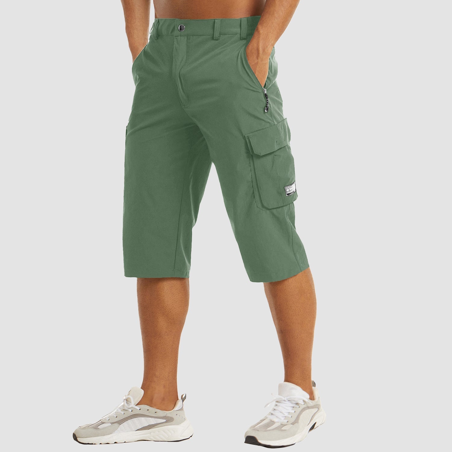 Pantaloncini cargo verdi da uomo, lunghezza al ginocchio, con tasche multiple e chiusura a zip, indossati con scarpe sportive bianche.