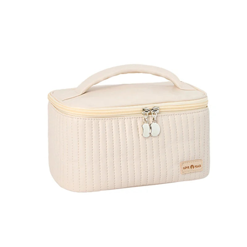 Astuccio cosmetico beige con cerniera, manico superiore e design trapuntato. Ideale per trucco e accessori da viaggio. Elegante e pratico.