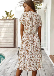 Abito estivo donna a pois marroni, maniche corte, lunghezza media, sfondo bianco. Moda casual, perfetto per giornate calde.