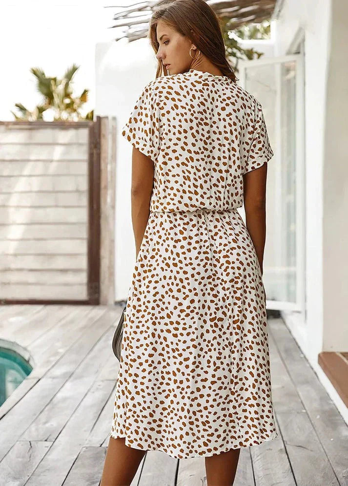 Abito estivo donna a pois marroni, maniche corte, lunghezza media, sfondo bianco. Moda casual, perfetto per giornate calde.