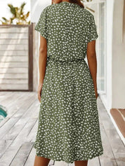 Abito estivo verde a pois bianchi, maniche corte, lunghezza media, indossato da donna su terrazza. Moda casual, abbigliamento femminile elegante.
