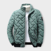 Giacca trapuntata verde uomo, collo alto, chiusura zip, tasche laterali, polsini e orlo a costine, ideale per l'inverno. Moda casual elegante.