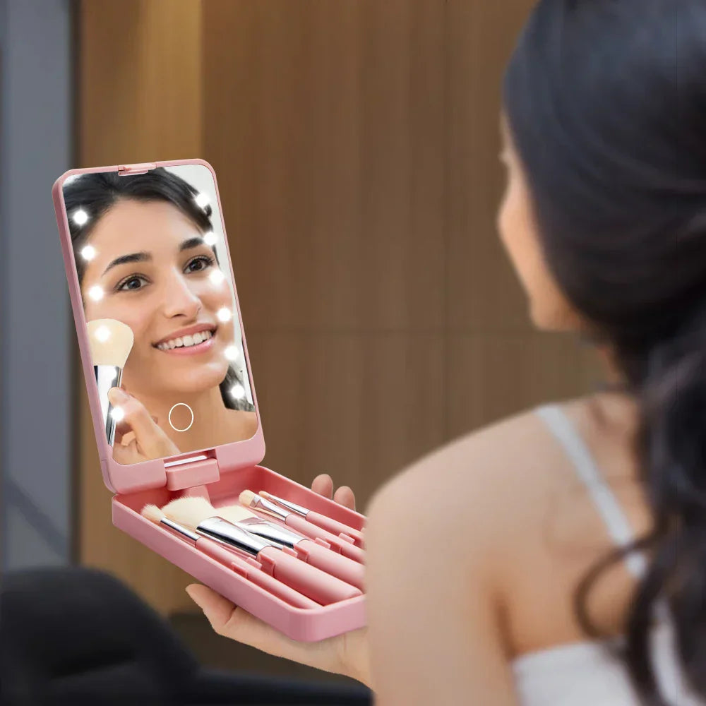 Donna che usa uno specchio portatile illuminato con set di pennelli da trucco rosa. Accessorio cosmetico ideale per trucco preciso e portatile.