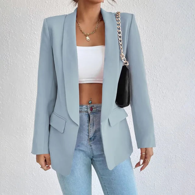 Giacca blazer donna azzurra elegante, abbinata a top bianco e jeans, con borsa a tracolla nera. Look moda casual chic.