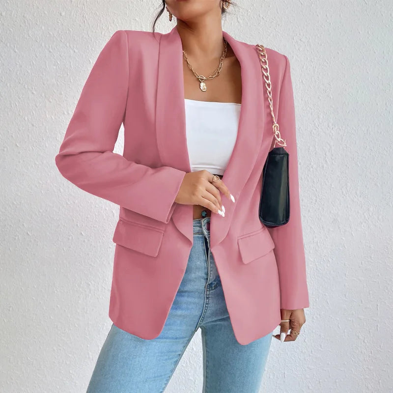 Giacca blazer rosa da donna, elegante e moderna, abbinata a top bianco e jeans. Accessorio borsa nera a catena. Moda femminile casual chic.