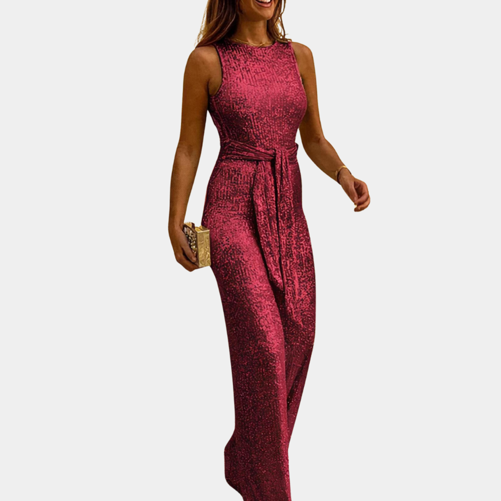 Donna in elegante tuta lunga rossa con paillettes, senza maniche, cintura in vita, clutch dorata. Abbigliamento da sera glamour.