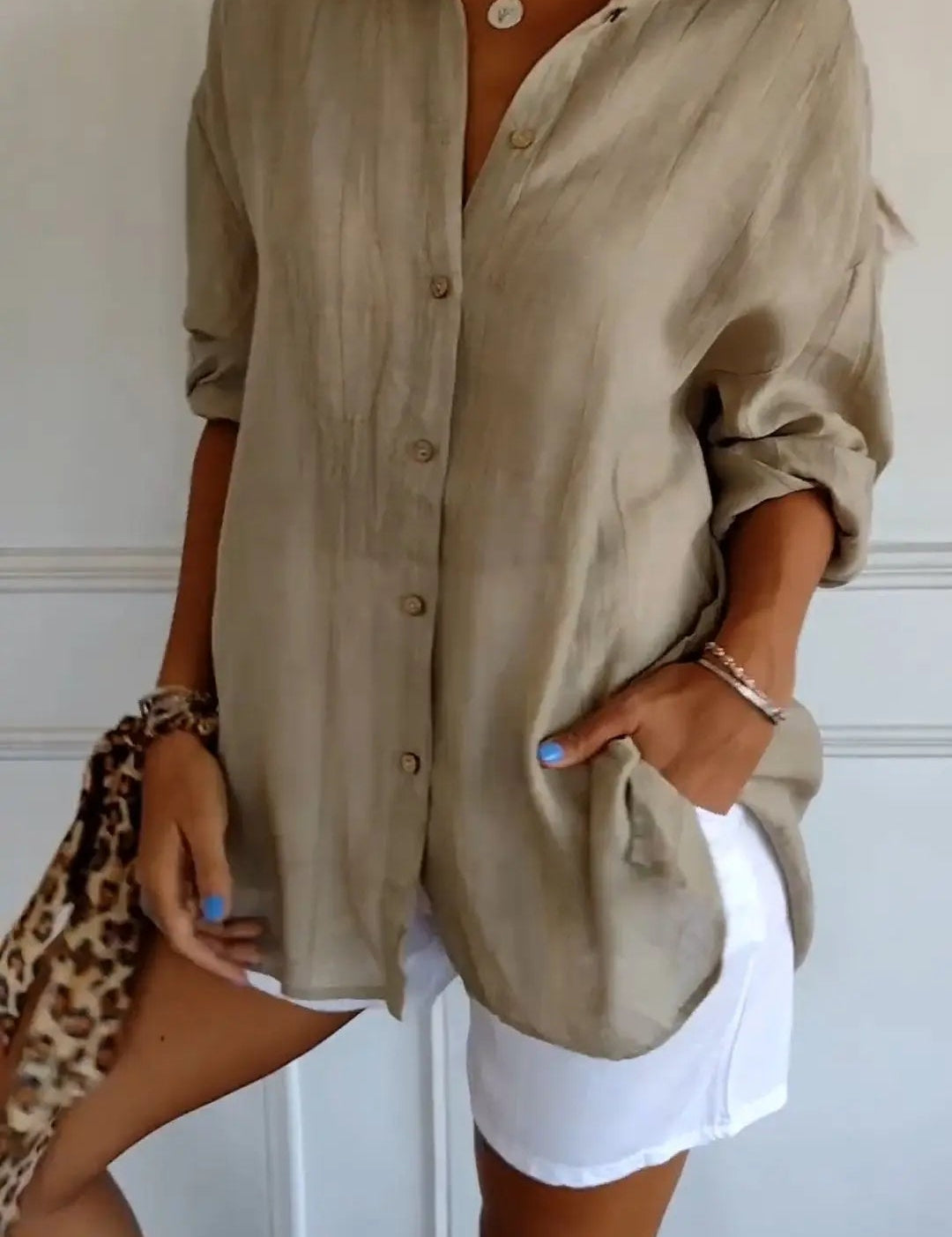 Camicia beige a maniche lunghe in lino, abbinata a pantaloncini bianchi. Look estivo casual, moda donna, stile elegante e rilassato.