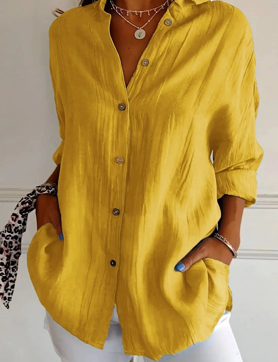 Camicia gialla da donna in lino, maniche lunghe, bottoni frontali, abbinata a pantaloni bianchi. Stile casual elegante, moda estiva.