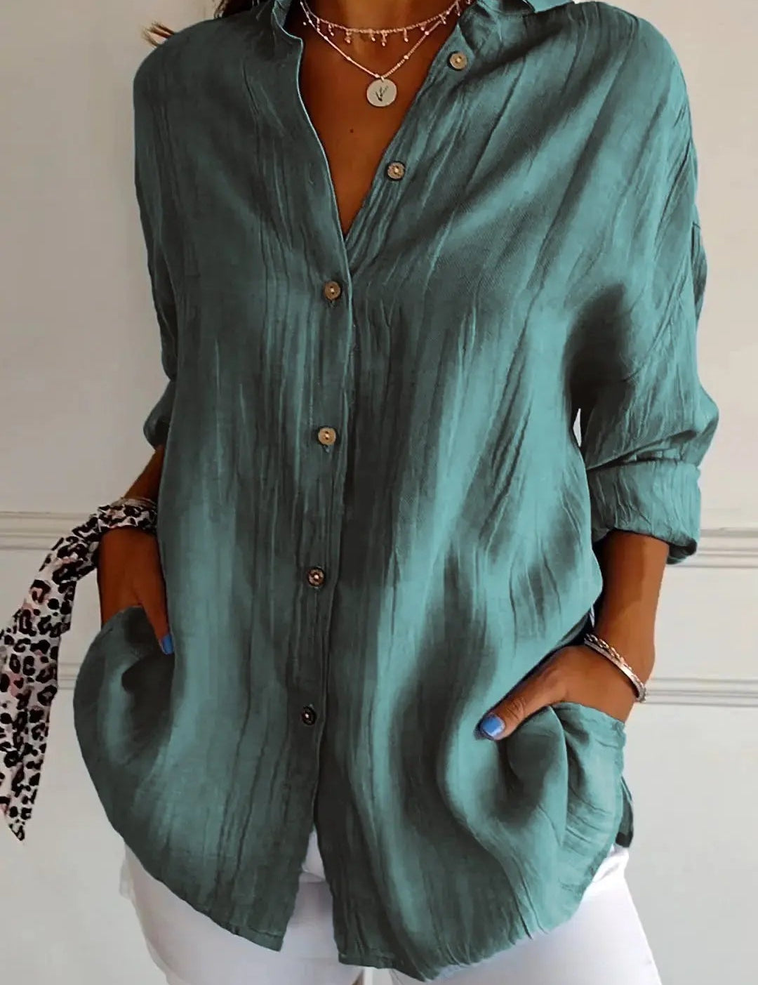 Camicia verde donna in lino, maniche lunghe, bottoni frontali, tasche laterali, abbinata a pantaloni bianchi. Stile casual elegante.