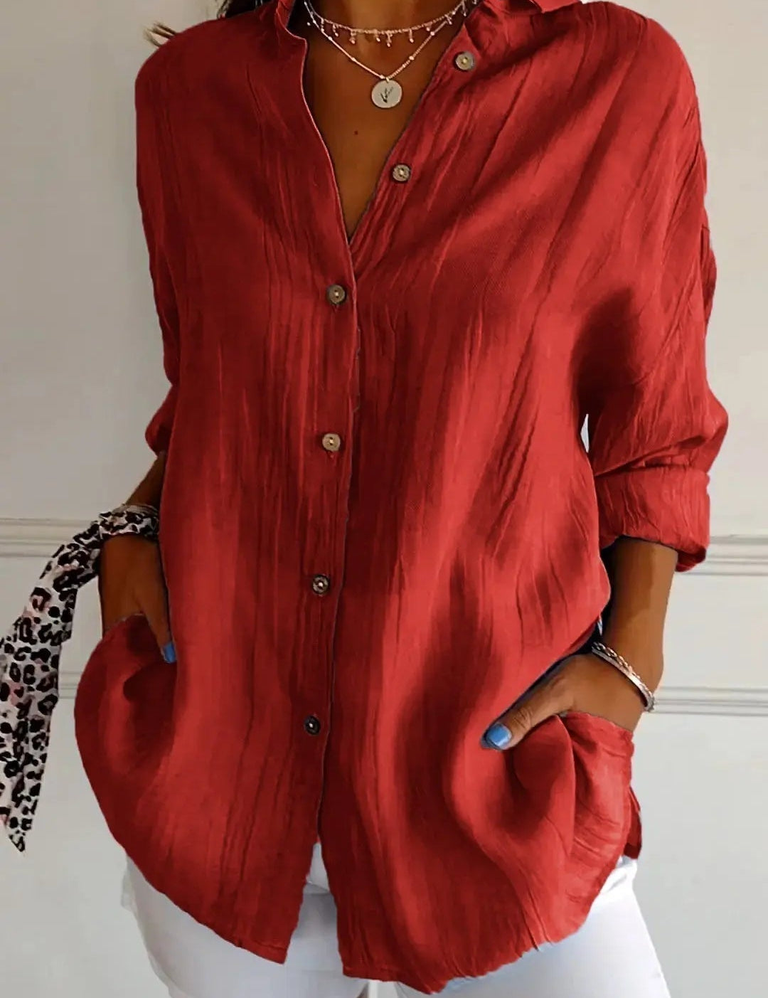 Camicia rossa da donna in tessuto leggero, maniche lunghe, bottoni frontali, abbinata a pantaloni bianchi. Stile casual elegante.
