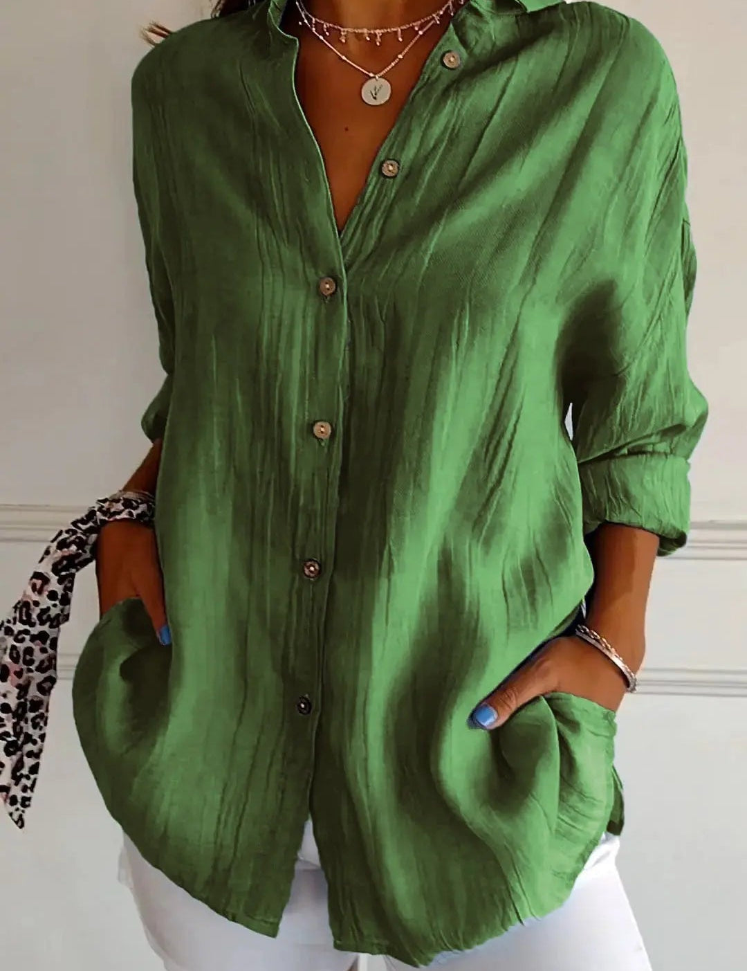Camicia verde in lino con bottoni, maniche lunghe, tasche frontali, abbinata a pantaloni bianchi. Stile casual elegante, moda donna.