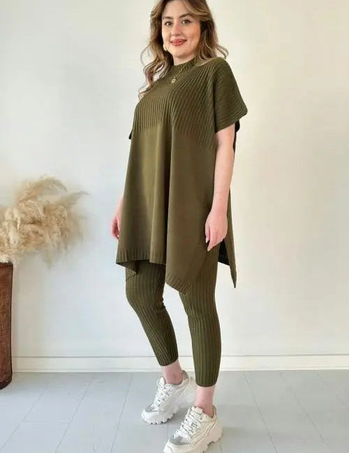Donna con tunica verde oliva e leggings a coste, scarpe da ginnastica bianche, sfondo neutro. Moda casual donna, abbigliamento comodo.