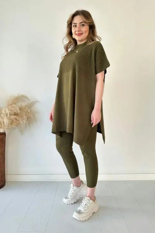 Donna con tunica verde oliva e leggings a coste, scarpe da ginnastica bianche, sfondo neutro. Moda casual donna, abbigliamento comodo.