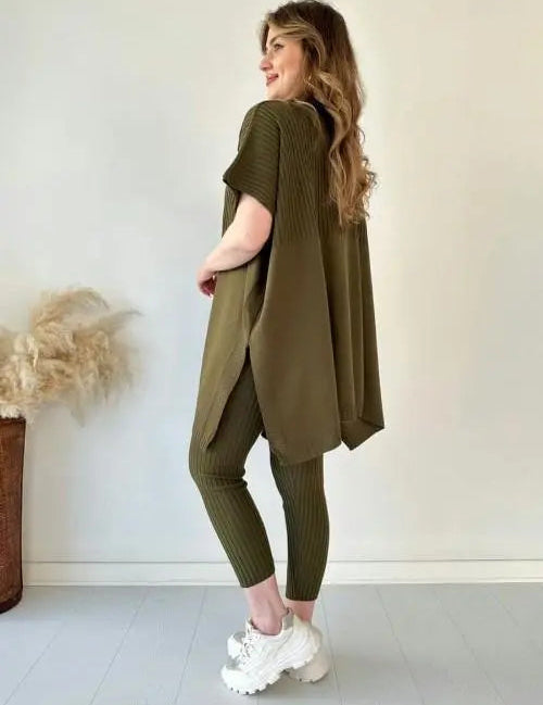 Donna in abbigliamento casual verde oliva, maglia oversize e leggings a coste, scarpe da ginnastica bianche. Sfondo neutro, stile moderno.