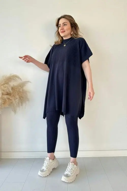 Donna in abito tunica blu scuro e leggings coordinati, scarpe da ginnastica bianche, posa su sfondo neutro. Moda casual, abbigliamento donna elegante.