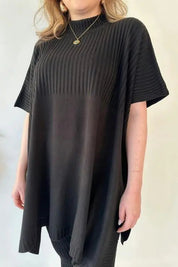 Donna con maglia oversize nera a coste, maniche corte, collo alto. Moda casual elegante, abbigliamento femminile, tendenza 2023.