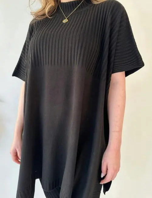 Donna con maglia oversize nera a coste, maniche corte, collo alto. Moda casual elegante, abbigliamento femminile, tendenza 2023.