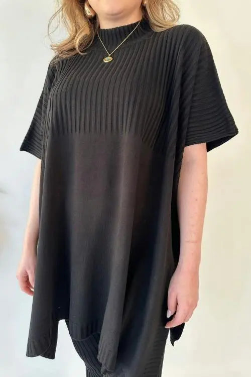 Donna con maglia oversize nera a coste, maniche corte, collo alto. Moda casual elegante, abbigliamento femminile, tendenza 2023.