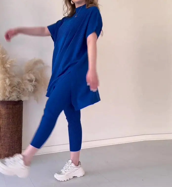 Abbigliamento donna: completo blu elegante con tunica e pantaloni, scarpe bianche. Moda casual, stile moderno, sfondo neutro.