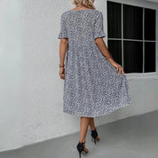 Abito estivo donna floreale bianco e nero, maniche corte, lunghezza al ginocchio, indossato da modella, sfondo bianco, moda casual elegante.