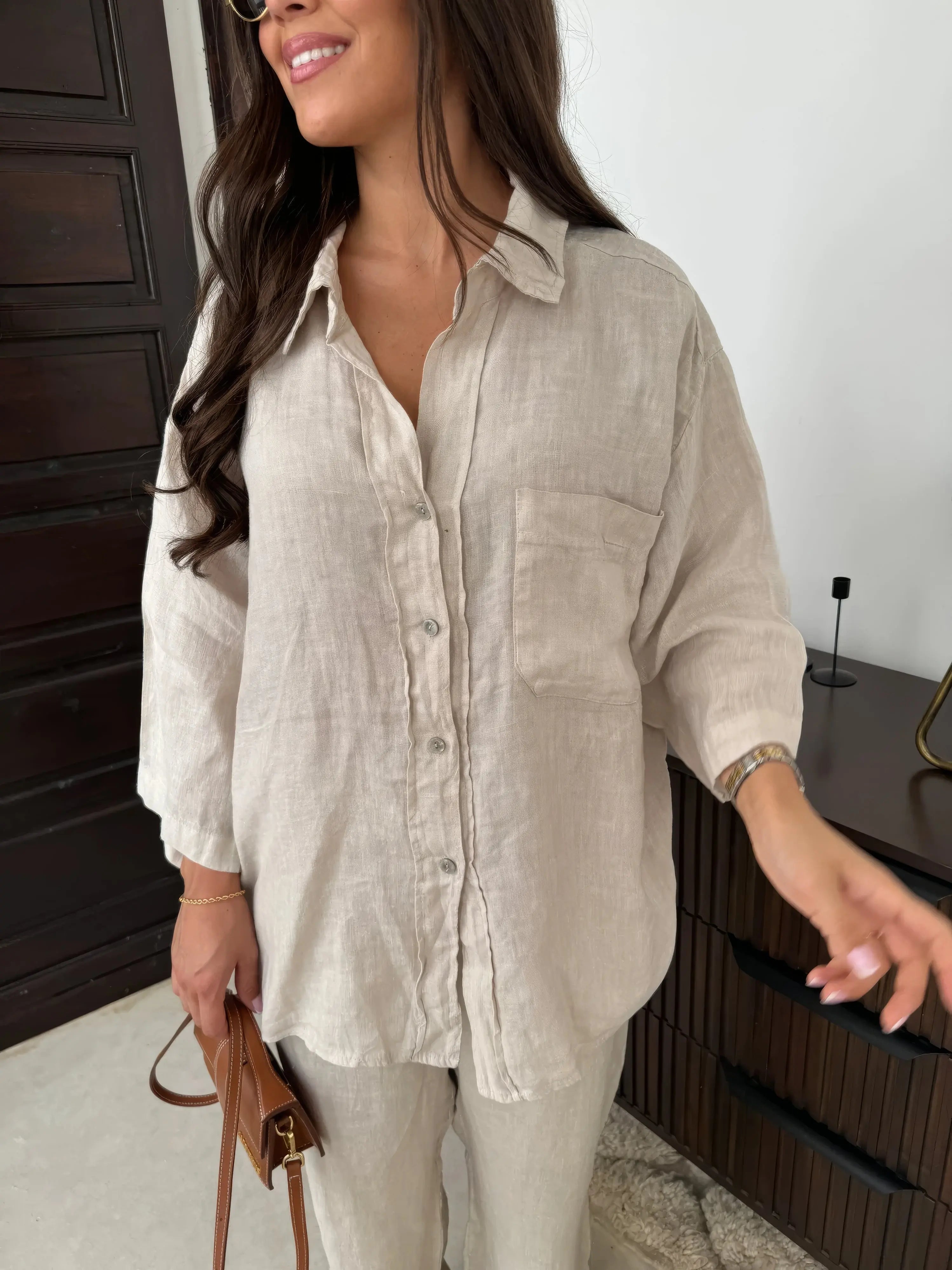 Camicia donna in lino beige, maniche lunghe, tasca frontale, abbinata a pantaloni coordinati. Look casual elegante, moda primavera estate.
