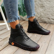 Scarpe da donna nere in pelle, stivaletti alla caviglia con suola robusta, indossati con jeans. Calzature moda autunno, stile casual e confortevole.