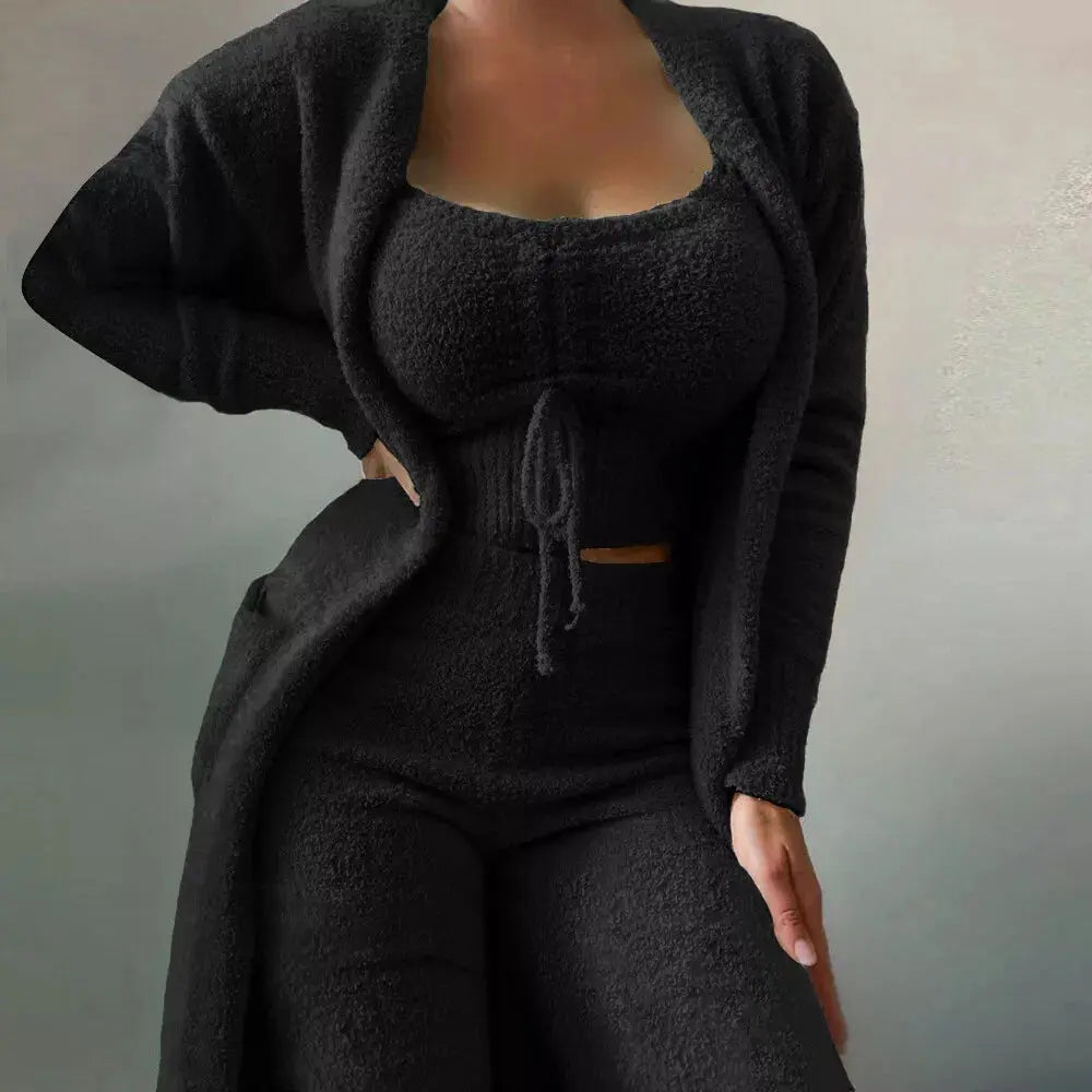 Donna in abbigliamento lounge nero, composto da cardigan, top e pantaloni a vita alta. Moda comoda, tessuto morbido, stile casual chic.