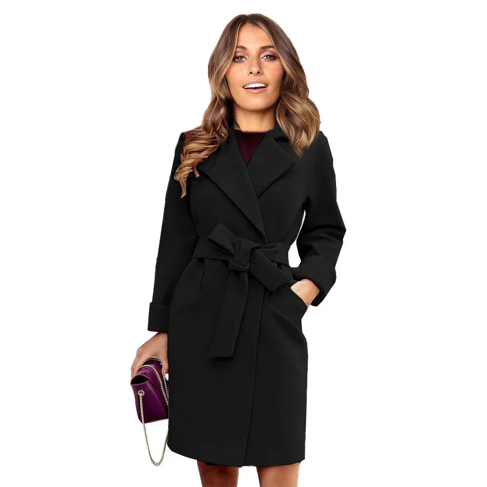 Cappotto nero elegante da donna con cintura, indossato da modella sorridente. Moda autunnale, abbigliamento femminile, stile sofisticato.