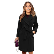 Cappotto nero elegante da donna con cintura, indossato da modella sorridente. Moda autunnale, abbigliamento femminile, stile sofisticato.