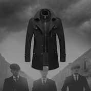 Cappotto uomo elegante nero, stile vintage, con colletto alto e bottoni, ispirato alla moda retrò. Sfondo grigio con figure sfocate.