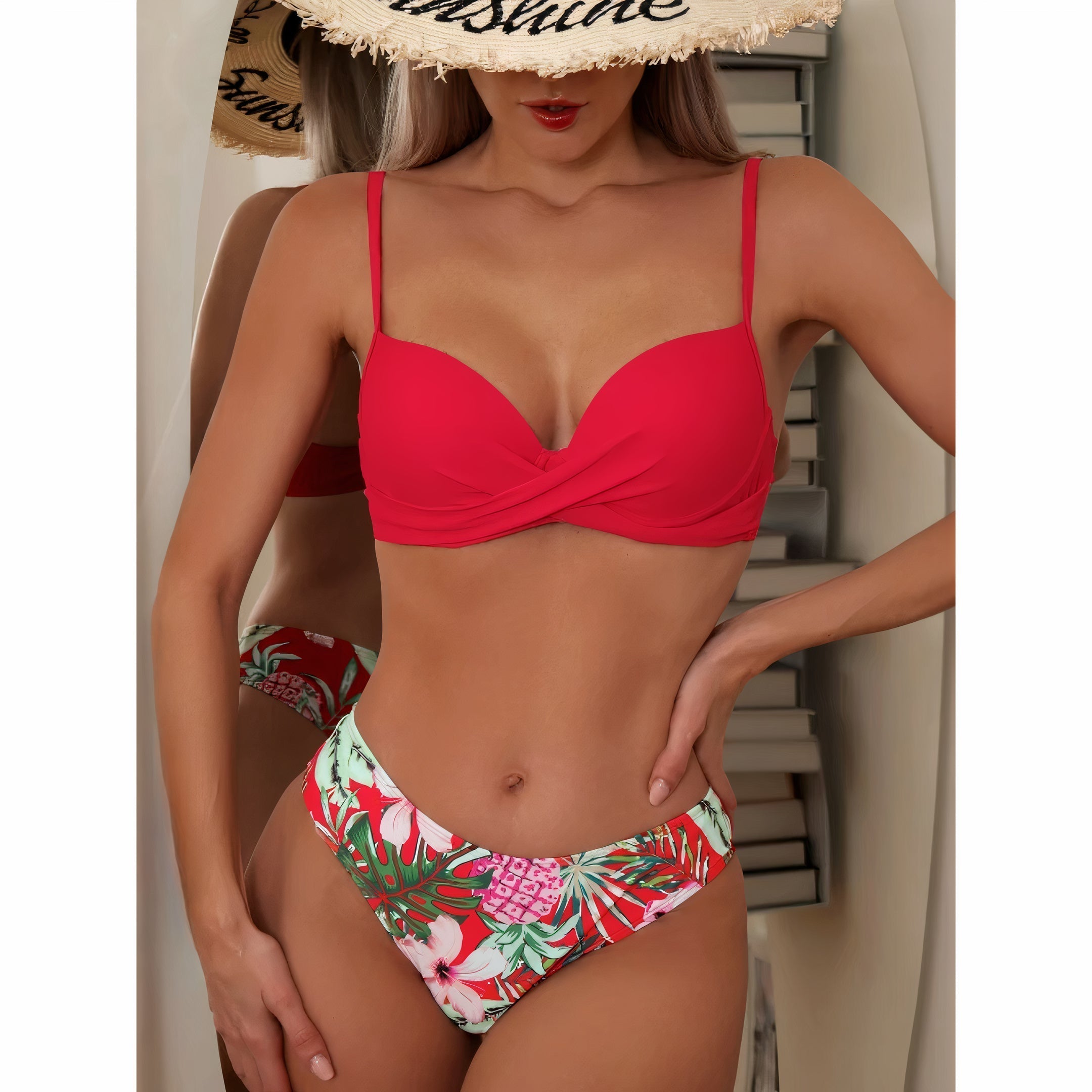Donna in bikini rosso e floreale, cappello di paglia, posa davanti a uno specchio. Moda mare, costumi da bagno estivi, tendenze 2023.