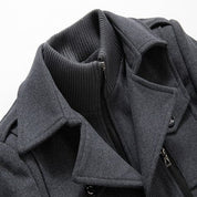 Giacca invernale uomo grigia con collo alto a coste, doppia chiusura con zip e bottoni. Elegante e calda, ideale per look casual e formali.