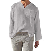 Camicia uomo bianca in lino, manica lunga, con taschino, scollo a V, abbinata a pantaloni a righe. Stile casual elegante, moda estiva.